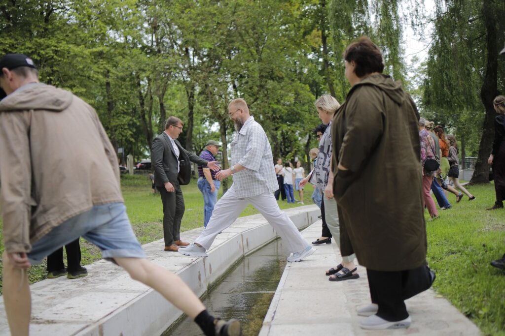 Plenero dalyvių žingsnis per upelį, istorinio Parko tiltelio vietoje
